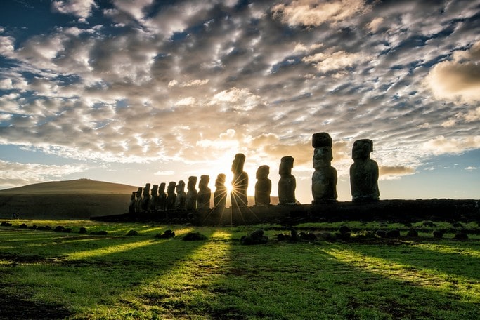 Siluety soch Moai v zapadajícím slunci