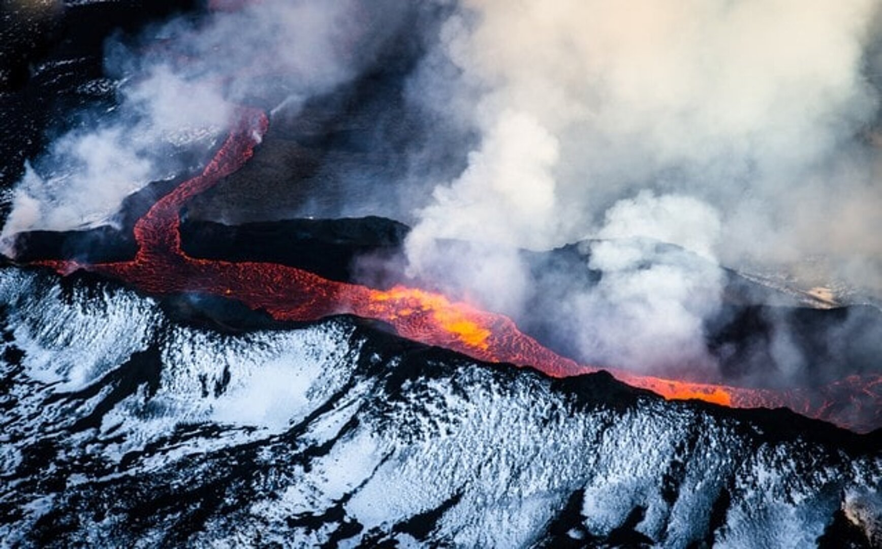 Island, záběr na kráter sopky, s vybuchující lávou