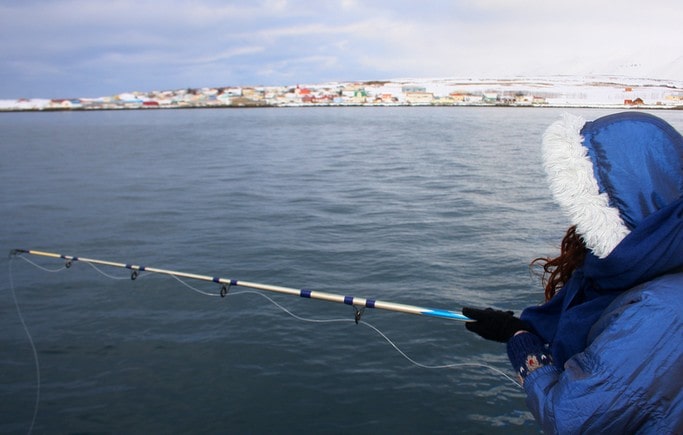 Dívka chytá ryby ve fjordu 