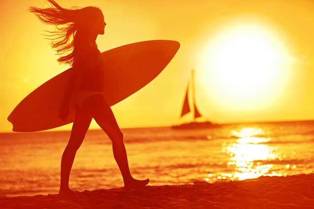 Dívka na pláži v západu slunce se surfem
